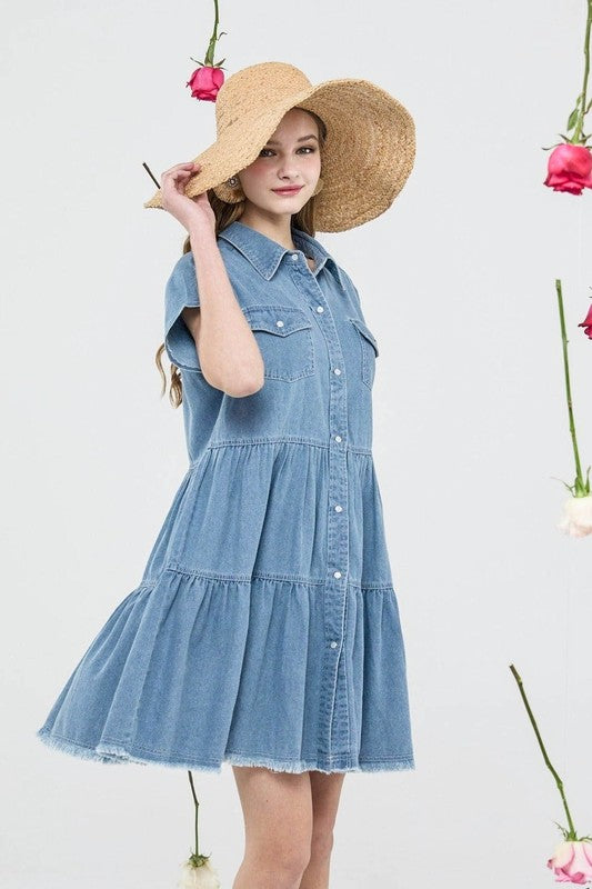 Woman wearing a denim dress and straw hat against a light background