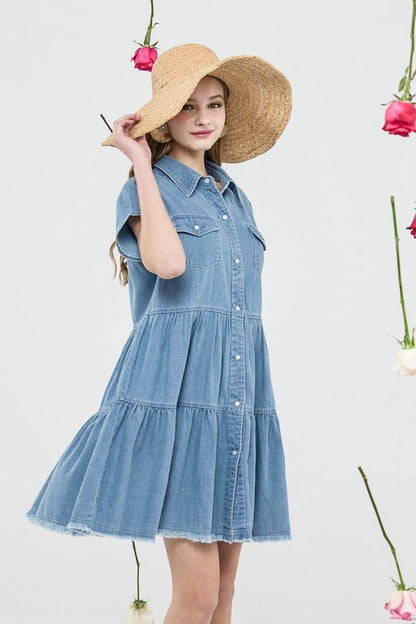 Woman wearing a denim dress and straw hat against a light background