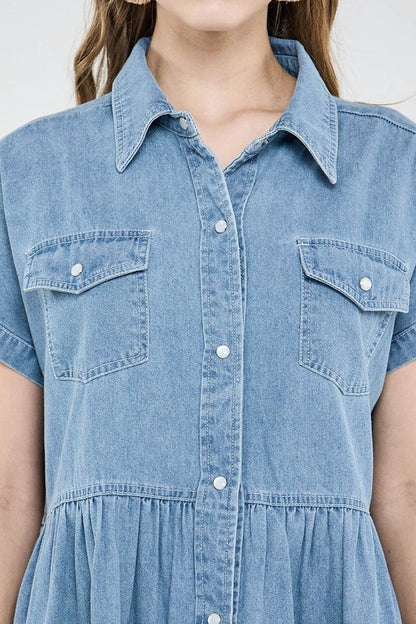 Close-up of a person wearing a light blue denim dress with short sleeves and button details.