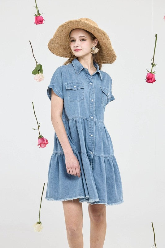 Woman wearing a denim dress and straw hat with flowers in the background