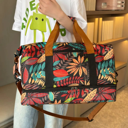 Colorful duffel bag with a vibrant leaf pattern in red, yellow, green, and blue, held by a person wearing a white cartoon t-shirt and light blue jeans. Bold and eye-catching—perfect for travel or casual outings.