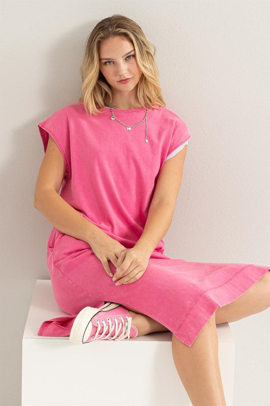 Woman models a comfortable pink midi dress with a relaxed fit and convenient side pockets.
