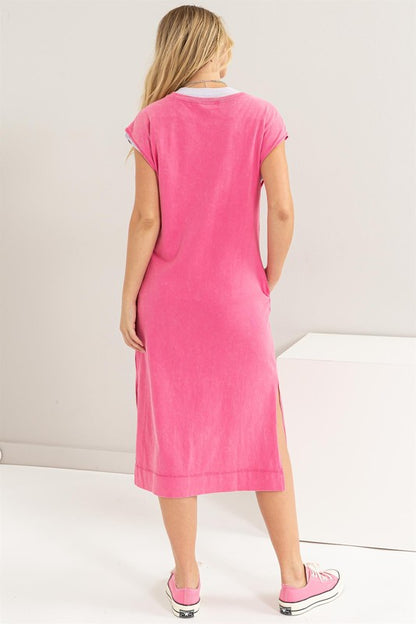 Woman models a comfortable pink midi dress with a relaxed fit and convenient side pockets, back view.