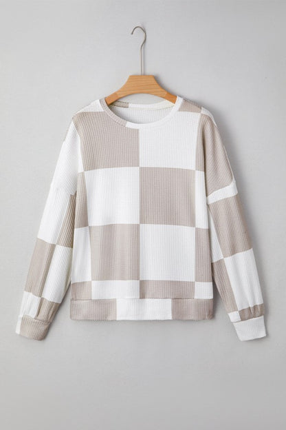Checkered sweater on a hanger against a gray background