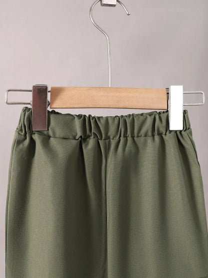 Green pants on a hanger against a gray background