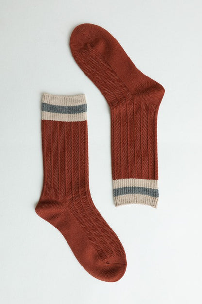 Rust ribbed crew socks with striped cuffs.