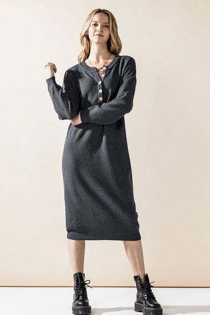 Woman wearing a button-front sweater midi dress with long sleeves and henley neckline.
