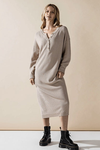 Woman wearing a button-front sweater midi dress with long sleeves and henley neckline.