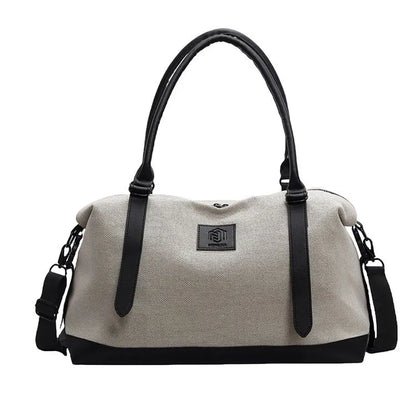Light beige duffel bag with black handles, bottom, and side straps, featuring a front logo patch—durable, minimalist, and suitable for everyday use.