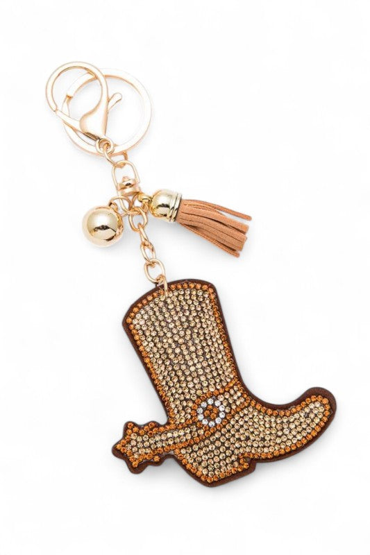 Cowboy boot keychain adorned with golden-brown rhinestones, featuring a spur detail, gold hardware, tassel, and bell, playful, western-inspired, and perfect for adding charm to bags or keys.