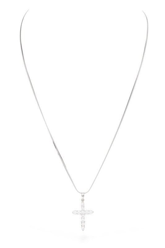 A silver cross pendant adorned with clear stones, hanging from a thin silver chain against a white background. The cross has a sleek design with stones set in a pattern that adds some bling to the piece.