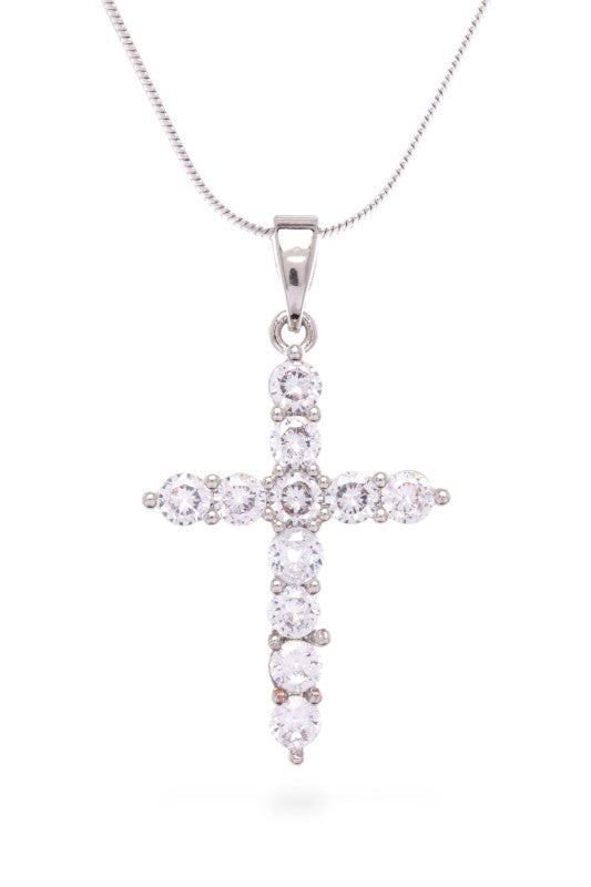 A silver cross pendant adorned with clear stones, hanging from a thin silver chain against a white background. The cross has a sleek design with stones set in a pattern that adds some bling to the piece.