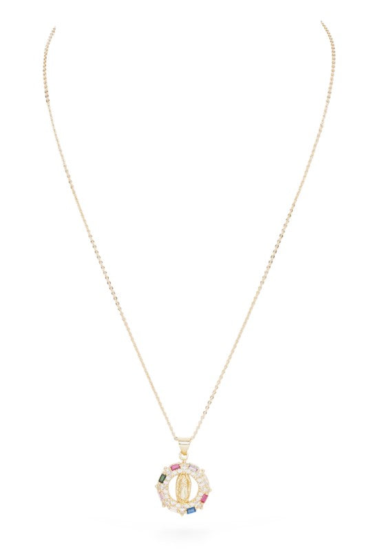 Gold necklace with a pendant. The pendant is circular with a gold Virgin Mary figure in the center. It's surrounded by a ring of clear and colored gemstones (pink, green, blue, peach). The background is white with a black border. 