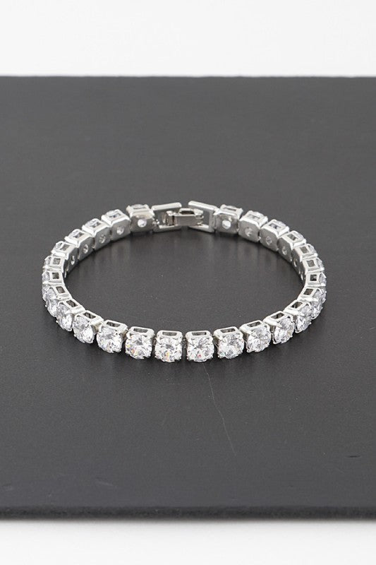 Silver tennis bracelet adorned with round-cut clear gemstones, set in a continuous row for an elegant and classic look.