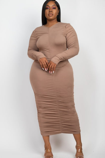 Model wears a flattering taupe ruched midi dress with long sleeves, showcasing elegant texture.