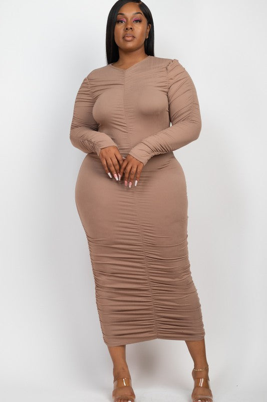 Model wears a flattering taupe ruched midi dress with long sleeves, showcasing elegant texture.