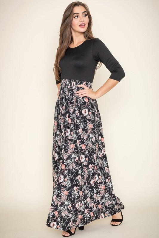 A woman wearing a navy blue top with a floral maxi skirt.