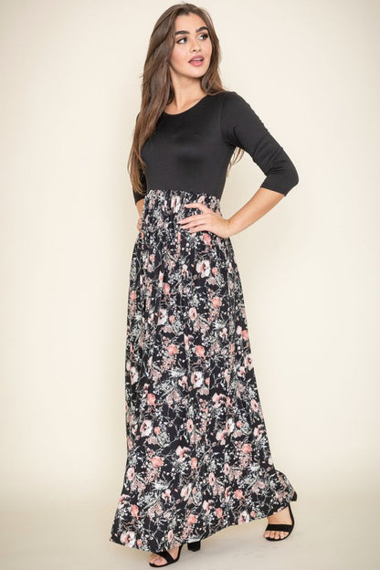 A woman wearing a navy blue top with a floral maxi skirt.