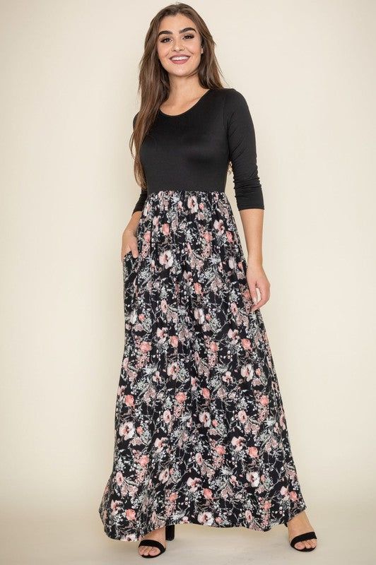 A woman wearing a navy blue top with a floral maxi skirt.
