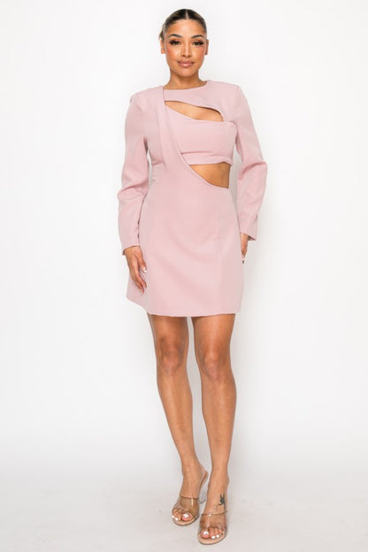 Woman wearing a long-sleeve mini dress with asymmetrical cutouts across the chest and midriff, styled against a plain white background.
