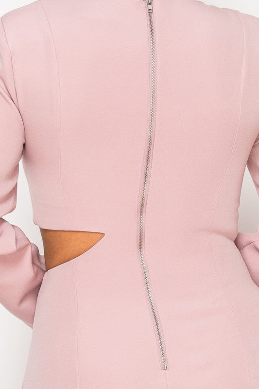 Woman wearing a long-sleeve mini dress with asymmetrical cutouts across the chest and midriff, styled against a plain white background.
