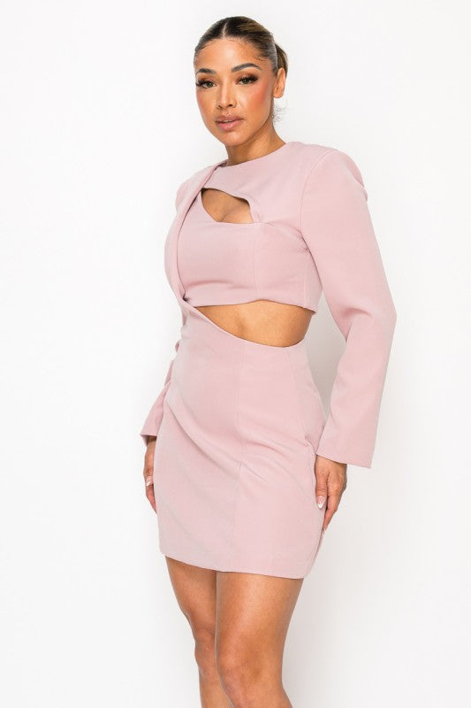 Woman wearing a long-sleeve mini dress with asymmetrical cutouts across the chest and midriff, styled against a plain white background.
