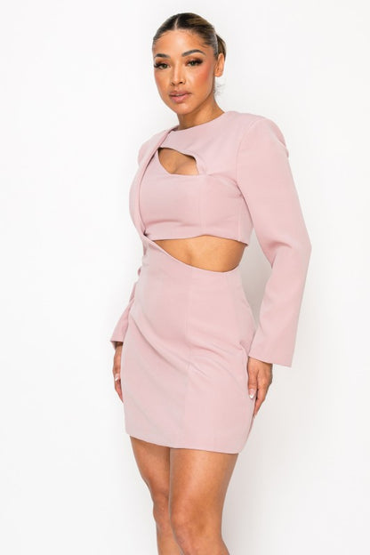 Woman wearing a long-sleeve mini dress with asymmetrical cutouts across the chest and midriff, styled against a plain white background.
