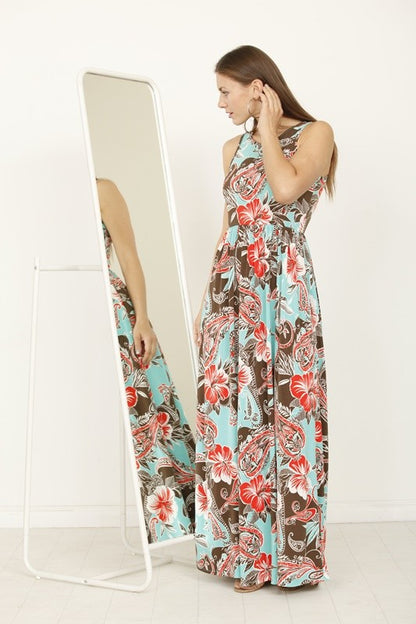 A woman posing in a long, sleeveless blue dress with a vibrant yellow floral pattern. 