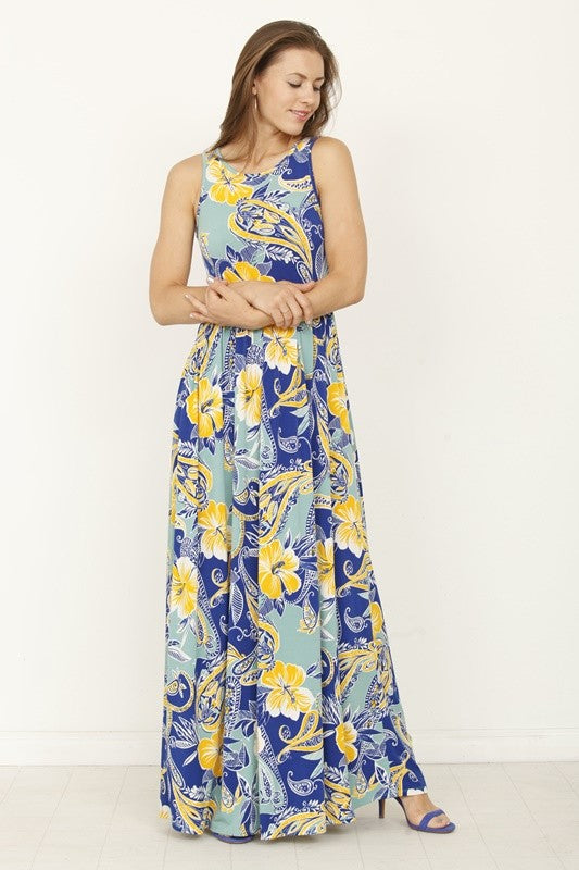 A woman posing in a long, sleeveless blue dress with a vibrant yellow floral pattern. 