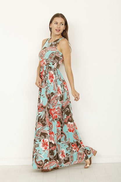 A woman posing in a long, sleeveless blue dress with a vibrant yellow floral pattern. 