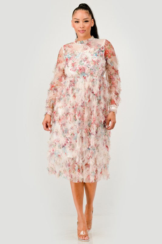 A woman wearing a Floral Ruffle Sheer Midi Dress, featuring an all over pastel floral print with cascading ruffle detailing for a soft, textured finish. 