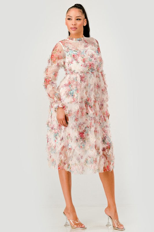 A woman wearing an elegant floral midi dress with sheer long sleeves, a high neck, and textured ruffled details for a romantic look.