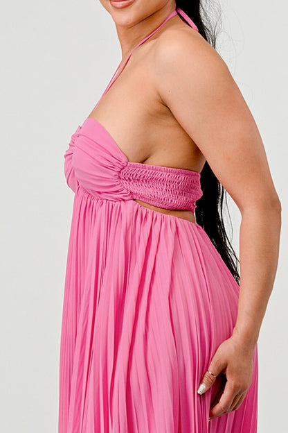 The image shows a woman with dark skin and long black hair wearing a hot pink, strapless maxi dress with a pleated skirt and a sweetheart neckline.