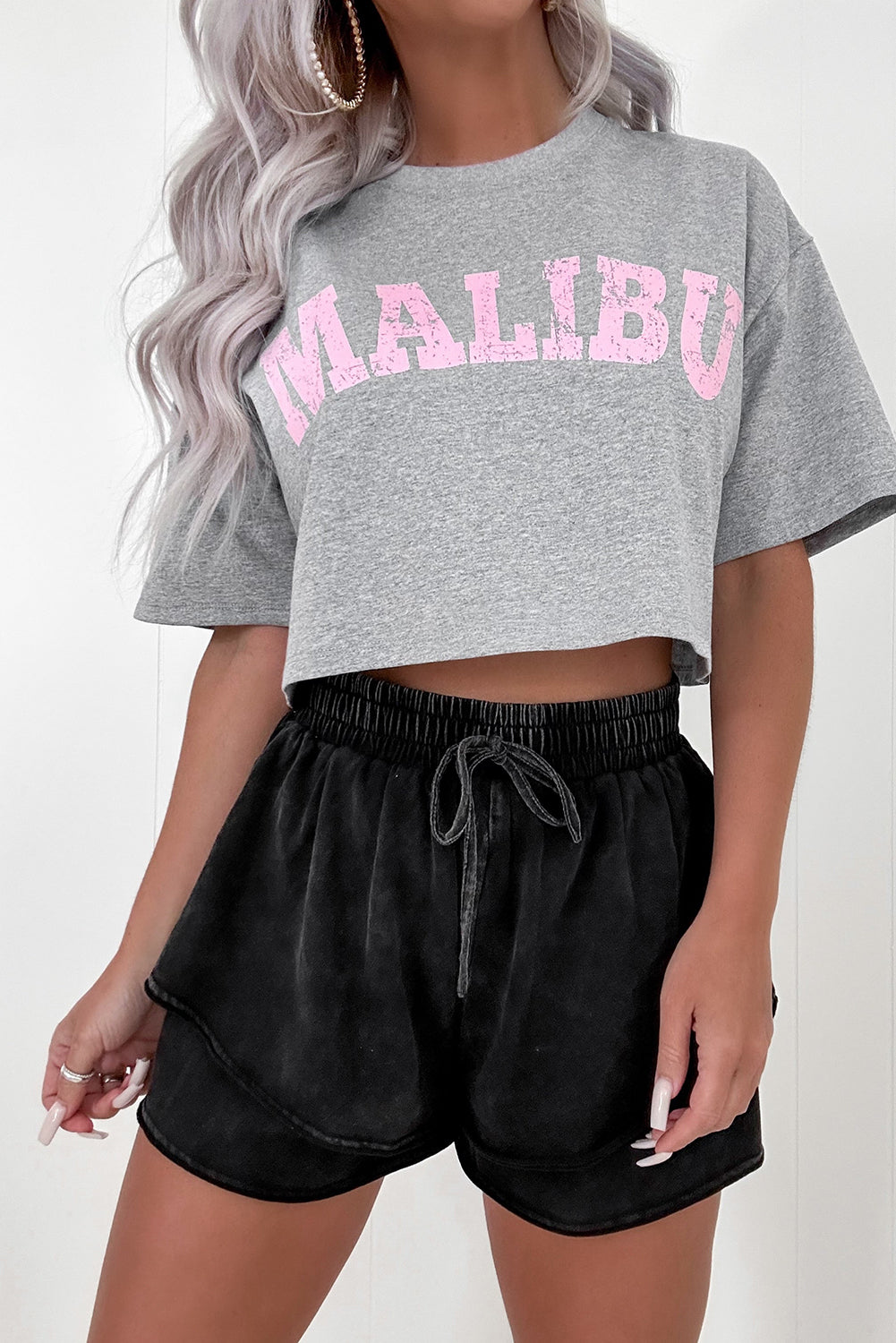 A person wearing black mineral wash French terry shorts with an elastic waistband and drawstring, paired with a white crop top. The shorts look soft, comfortable, and ideal for casual wear, lounging, or street style