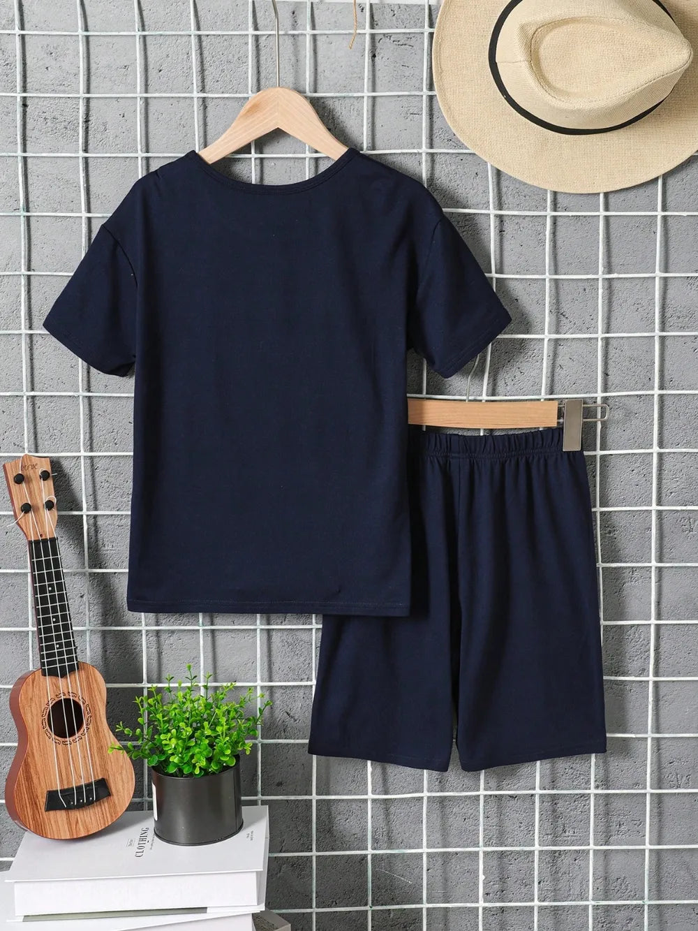 Navy blue t-shirt and shorts set with a hat and ukulele on a tiled wall background