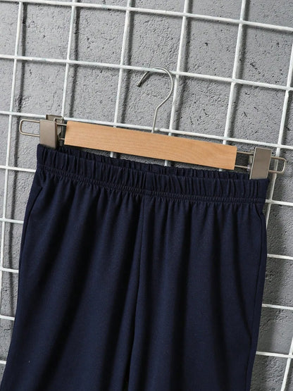 Black pants on a wooden hanger against a grid wall.