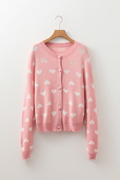 A pink Heart Button Front Sweater hanging on wall