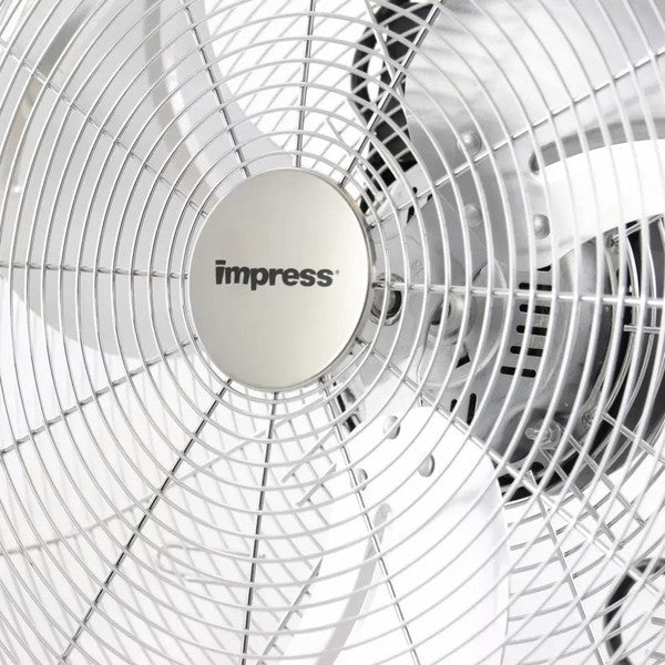 Metallic Impress floor fan with five blades and circular grille—mounted on a sturdy angled stand with rubber feet, designed for high-velocity cooling.