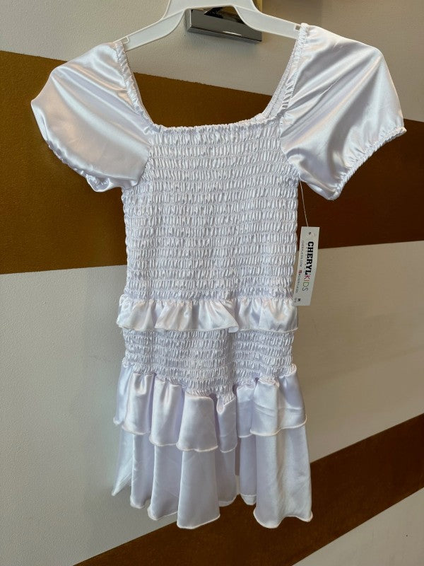 White smocked dress on a hanger with a brown and white striped background
