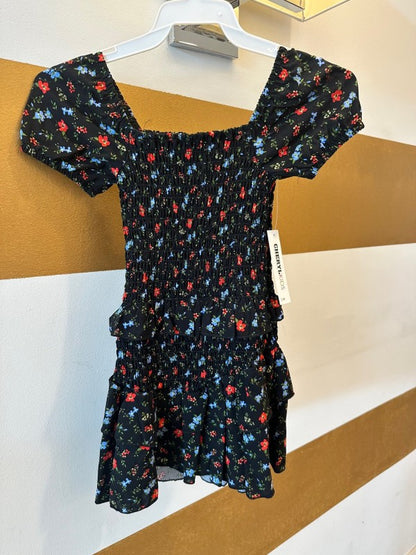 Black floral dress on a hanger against a white and brown background