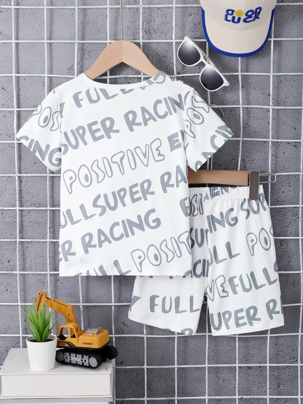 White t-shirt with text and shorts on a hanger against a tiled wall.