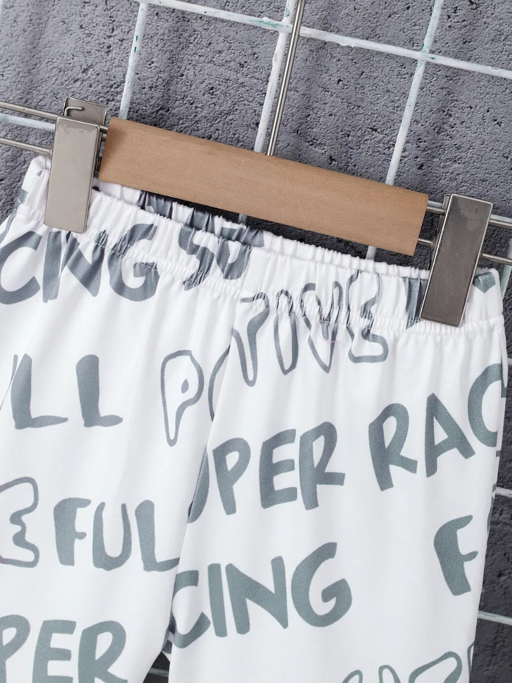 White shorts with gray text on a hanger against a tiled wall background