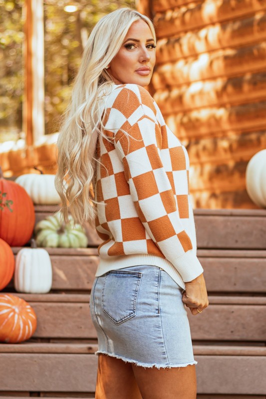 Woman models a cozy orange and white checkered hooded sweater with a kangaroo pocket, side view.