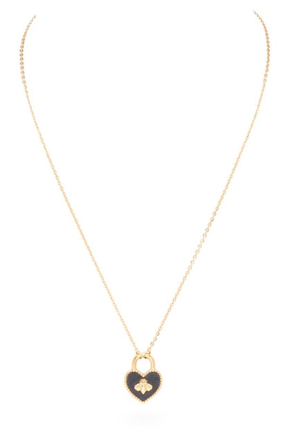 A necklace with a heart-shaped pendant. The pendant is designed like a padlock with a gold outline and a black background. There's a gold bee in the middle of the heart. The chain is gold too.