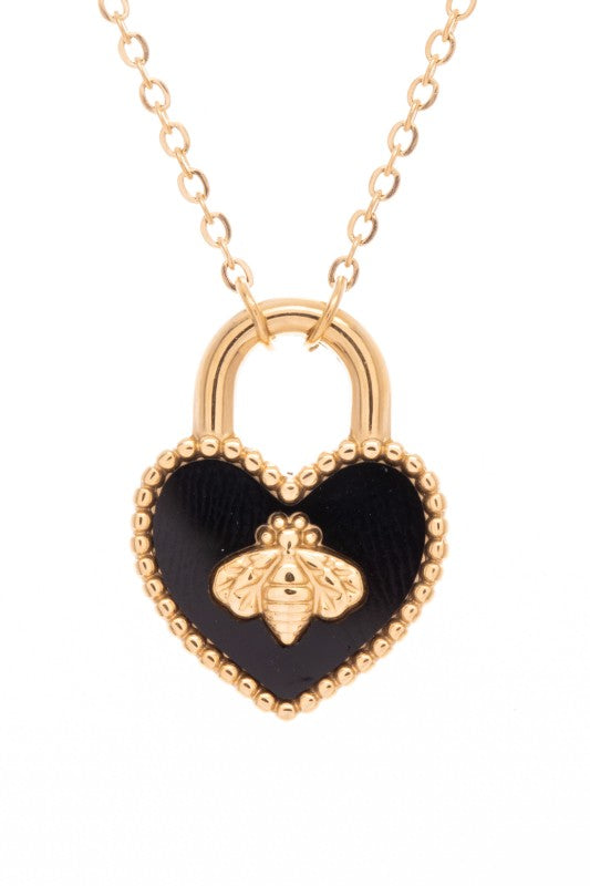 A necklace with a heart-shaped pendant. The pendant is designed like a padlock with a gold outline and a black background. There's a gold bee in the middle of the heart. The chain is gold too.