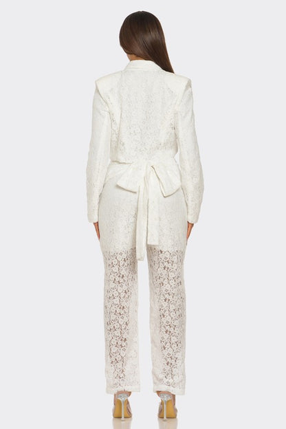 The woman is rocking a chic white suit with a plunging blazer and lace details on the pants. 