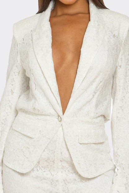 The woman is rocking a chic white suit with a plunging blazer and lace details on the pants. 