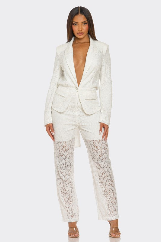 The woman is rocking a chic white suit with a plunging blazer and lace details on the pants. 