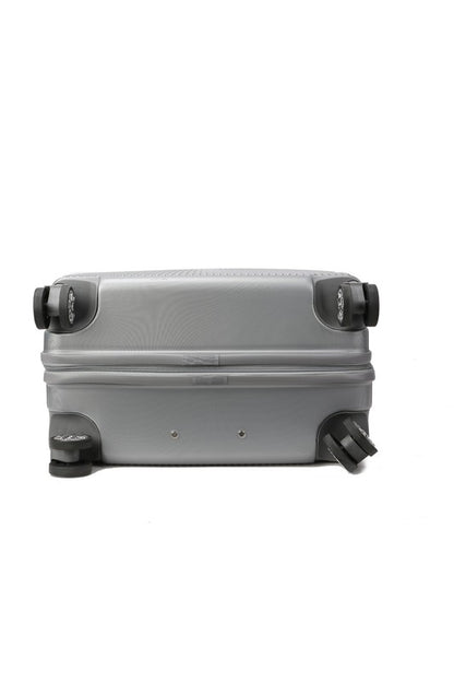 Silver hard-shell suitcase with vertical ribbed texture, extended telescopic handle, and four spinner wheels—positioned upright on a wooden floor.
