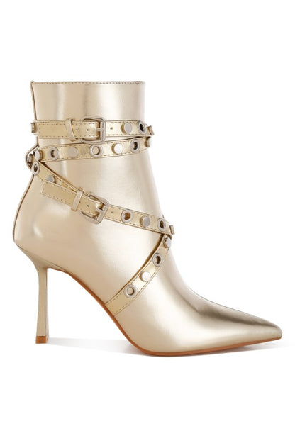 Gold high-heeled boots with studded details on a white background